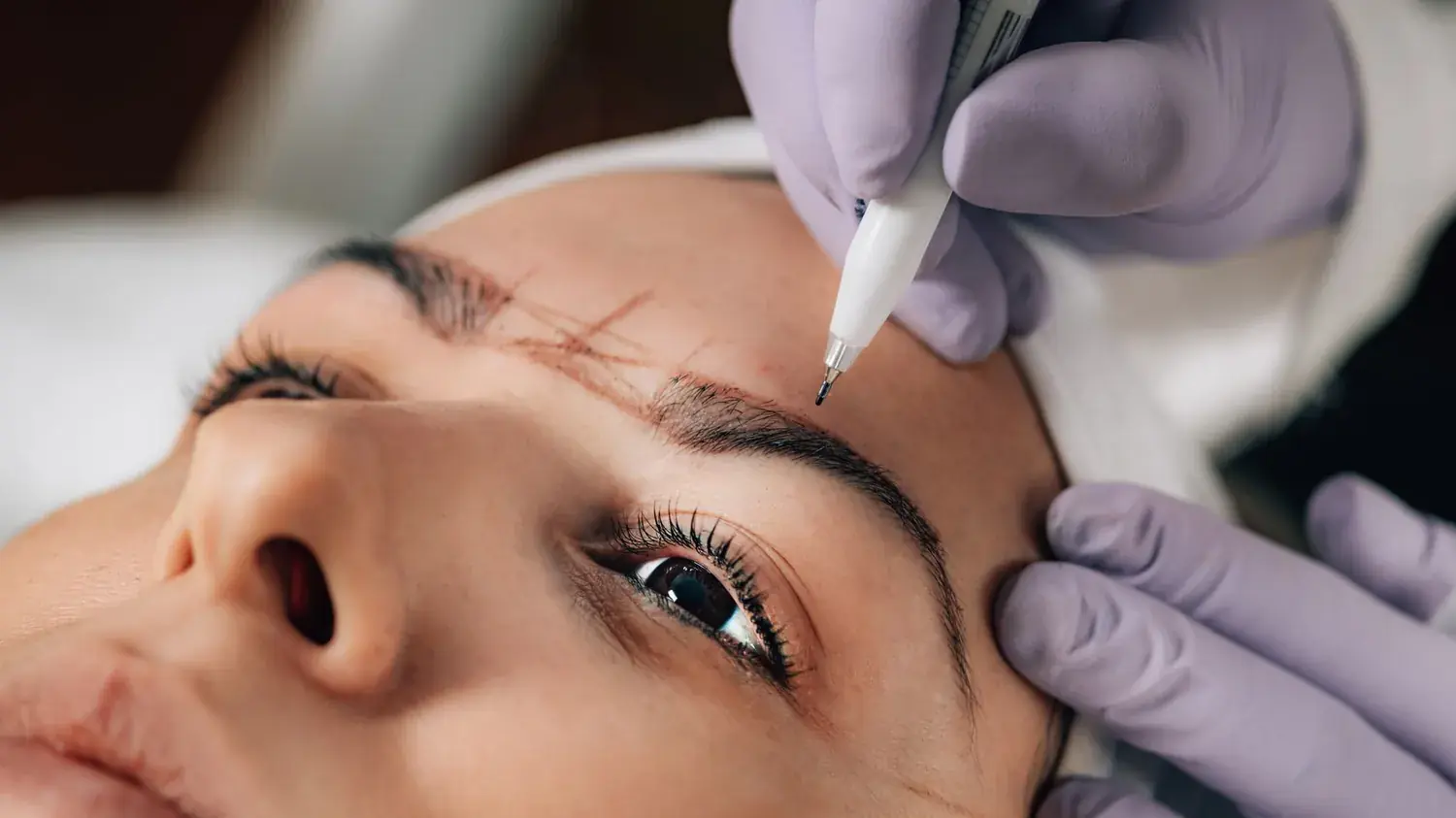 Geste de microblading au stylo sur le sourcil, gants à usage unique