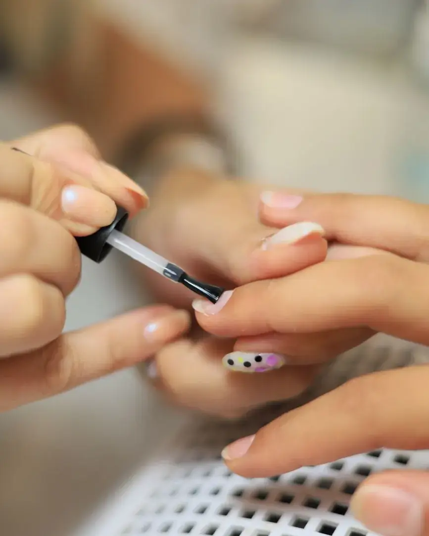 Pose de vernis semi-permanent sur les ongles, geste en gros plan