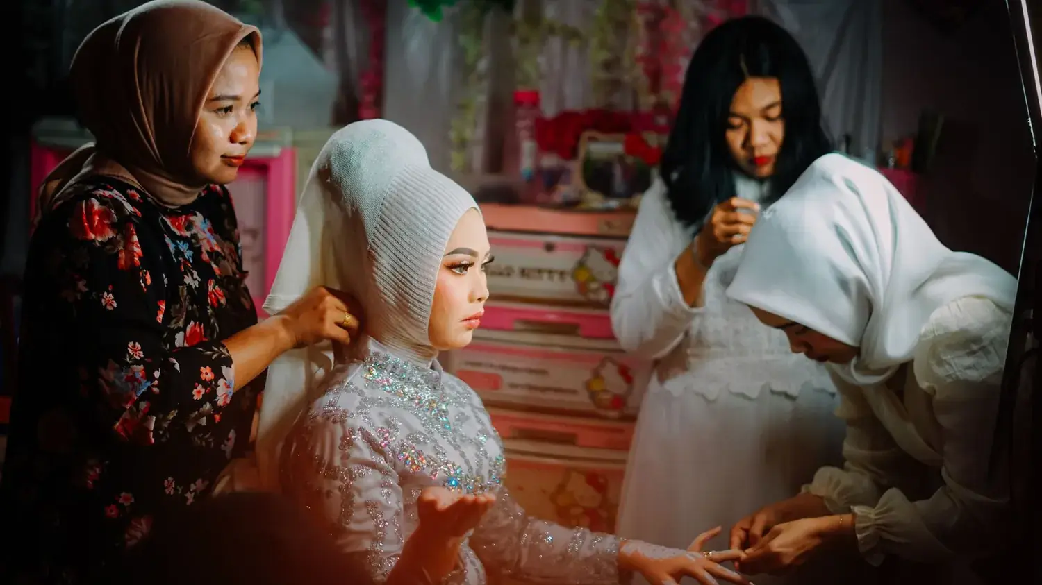 A veiled bride getting ready, surrounded by family