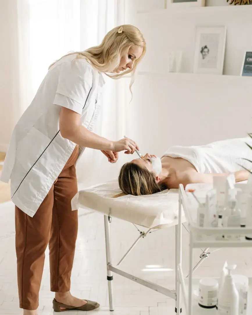 Facial treatment on a treatment table, practitioner in a white coat